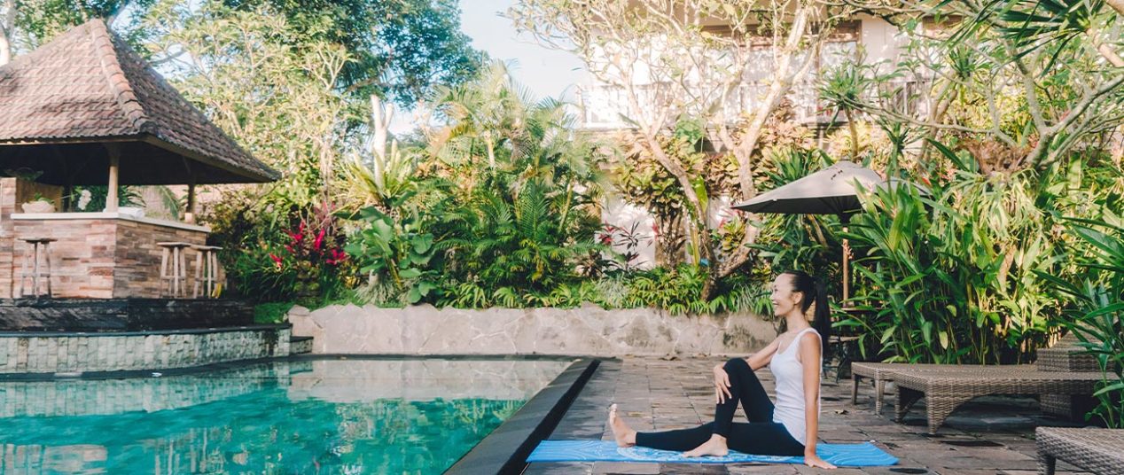 woman by villa pool doing yoga